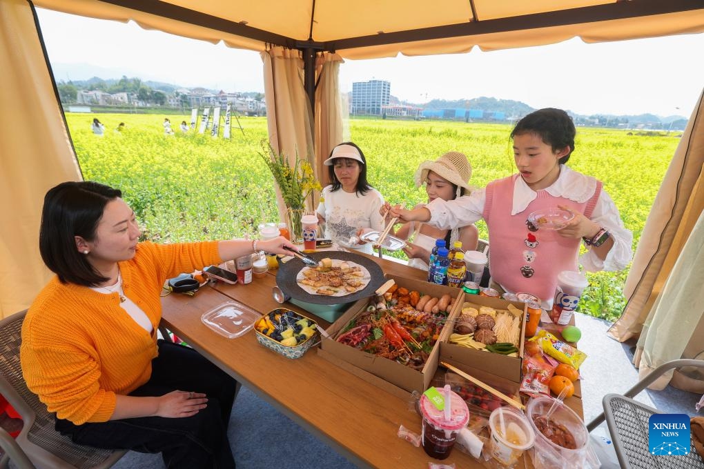 Tourists enjoy food in a tent in a rapeseed flower field in Jiande City, east China's Zhejiang Province, March 23, 2025. In Zhejiang Province, as the temperature rises, people go out of their homes to enjoy the blossoms in the spring time, showing a lifestyle in harmony with nature. (Photo: Xinhua)
