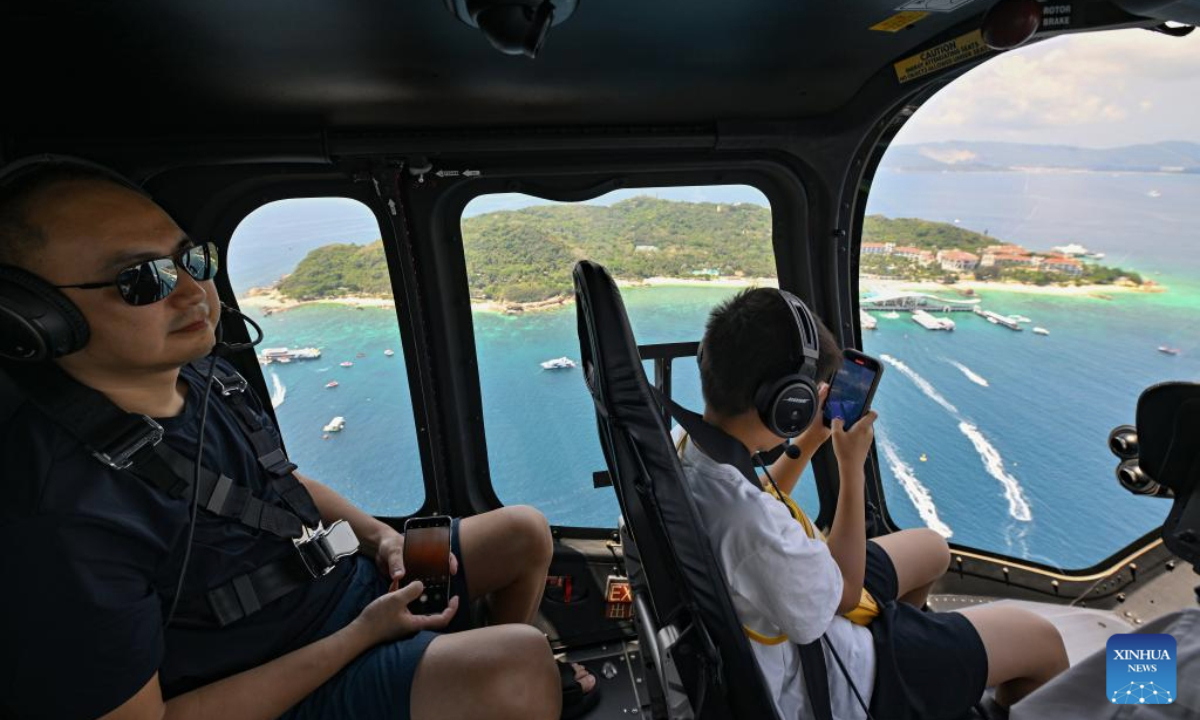 Tourists enjoy a helicopter sightseeing tour in Sanya, south China's Hainan Province, May 3, 2025. Low-altitude tourism activities such as paragliding and parachuting have become trendy among tourists to China's island province of Hainan during the May Day holiday. (Xinhua/Guo Cheng)