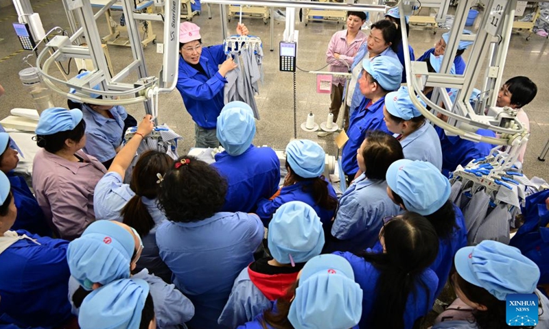 A staff member of a garment enterprise in an industrial park trains workers on new equipment and skills in Jimo District of Qingdao City, east China's Shandong Province, on March 25, 2025. Jimo District of Qingdao City has continuously guided private enterprises to increase R&D and investment in new technologies, new equipment and new processing technology in recent years. (Photo: Xinhua)