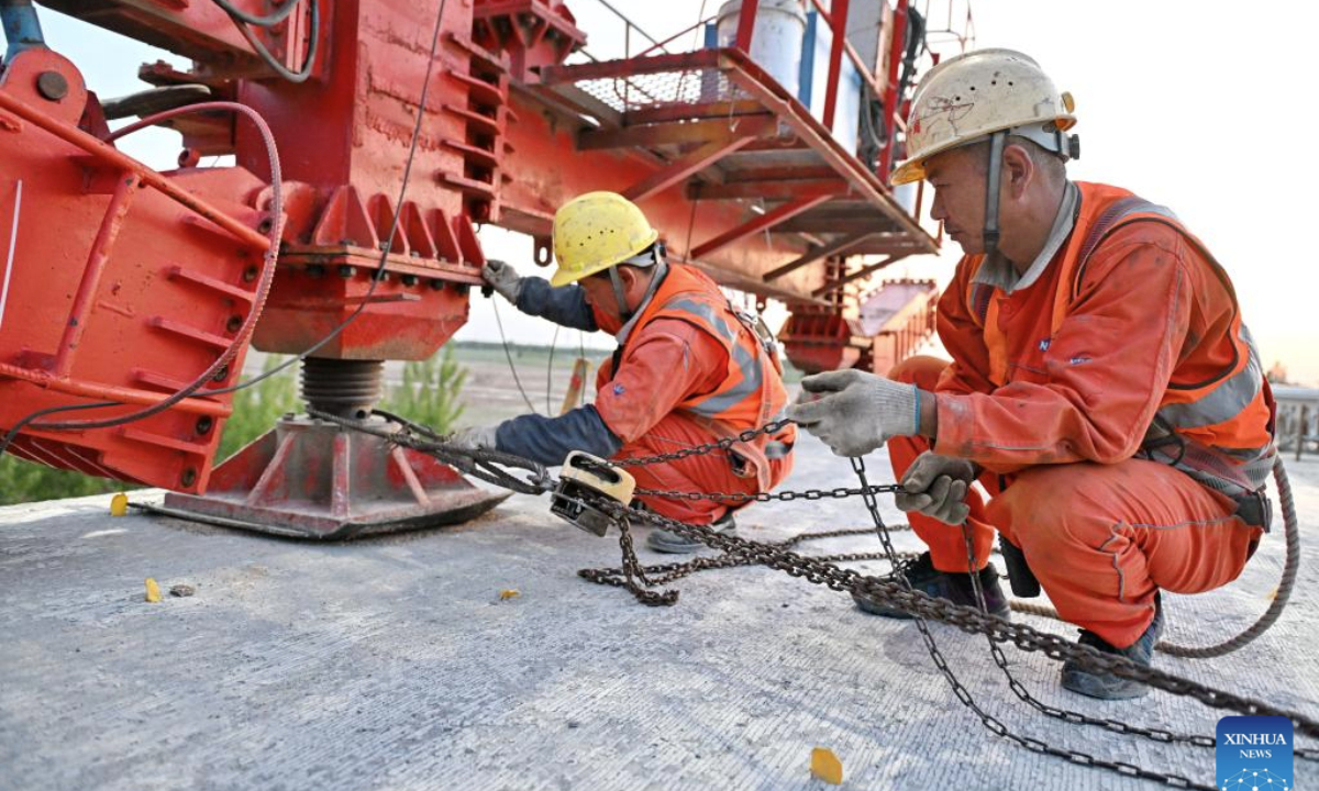 Workers erect a box girder at the construction site of a mega bridge in the Hebei section of the Xiong'an-Shangqiu high-speed railway in north China's Hebei Province, April 27, 2025. Girder erection work in the Hebei section of Xiong'an-Shangqiu high-speed railway was fully completed on Sunday as the last box girder was erected on a mega bridge. The 552-kilometer-long railway will connect Xiong'an in north China's Hebei Province and Shangqiu in central China's Henan Province with a designed speed of 350 kilometers per hour. (Xinhua/Mu Yu)