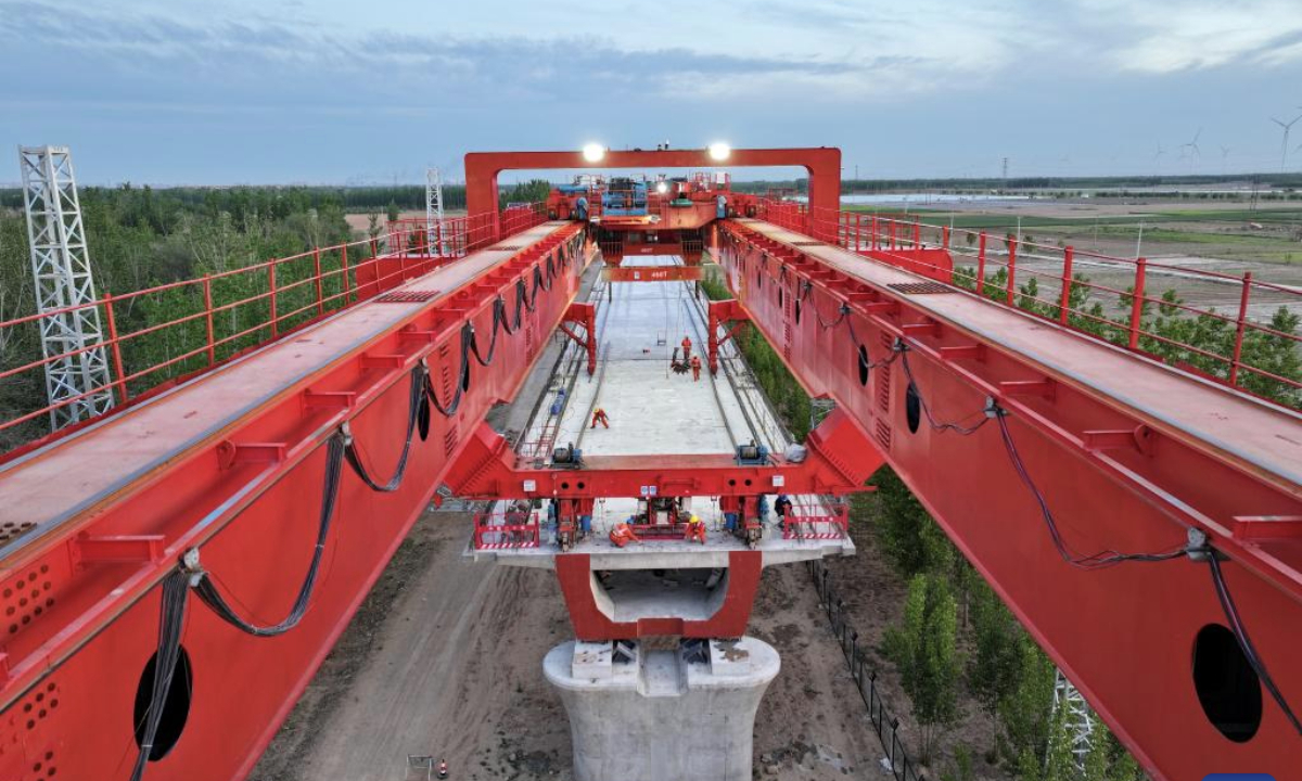 An aerial drone photo taken on April 27, 2025 shows workers erecting a box girder at the construction site of a mega bridge in the Hebei section of the Xiong'an-Shangqiu high-speed railway in north China's Hebei Province. Girder erection work in the Hebei section of Xiong'an-Shangqiu high-speed railway was fully completed on Sunday as the last box girder was erected on a mega bridge. The 552-kilometer-long railway will connect Xiong'an in north China's Hebei Province and Shangqiu in central China's Henan Province with a designed speed of 350 kilometers per hour. (Xinhua/Mu Yu)