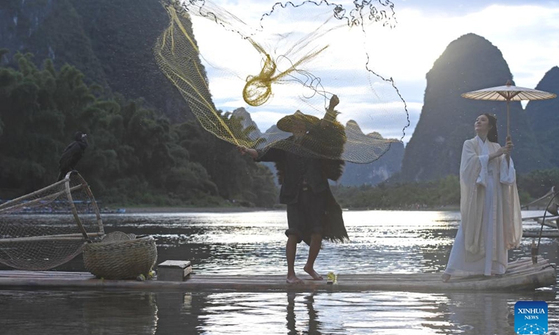 A tourist poses for photos with a fisherman on a bamboo raft on the Lijiang River in Yangshuo County of Guilin, south China's Guangxi Zhuang Autonomous Region, Aug. 25, 2022. Guilin, renowned for its breathtaking karst landscape, is one of China's most iconic destinations. Nestled in the Guangxi Zhuang Autonomous Region, Guilin is celebrated for its stunning natural beauty, with limestone peaks and serene rivers that attract visitors from around the world. Its unique topography and vibrant culture make it a cornerstone of Chinese tourism. (Photo: Xinhua)