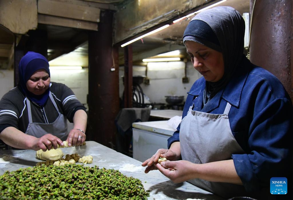 Two Syrian women stuff dough with crushed pistachios while preparing maamoul cookies at a traditional workshop in Damascus, Syria, on March 27, 2025. As Eid al-Fitr approaches, bakeries across Damascus are busy preparing maamoul and other confections made with wheat flour and stuffed with pistachios, walnuts or dates. (Photo: Xinhua)