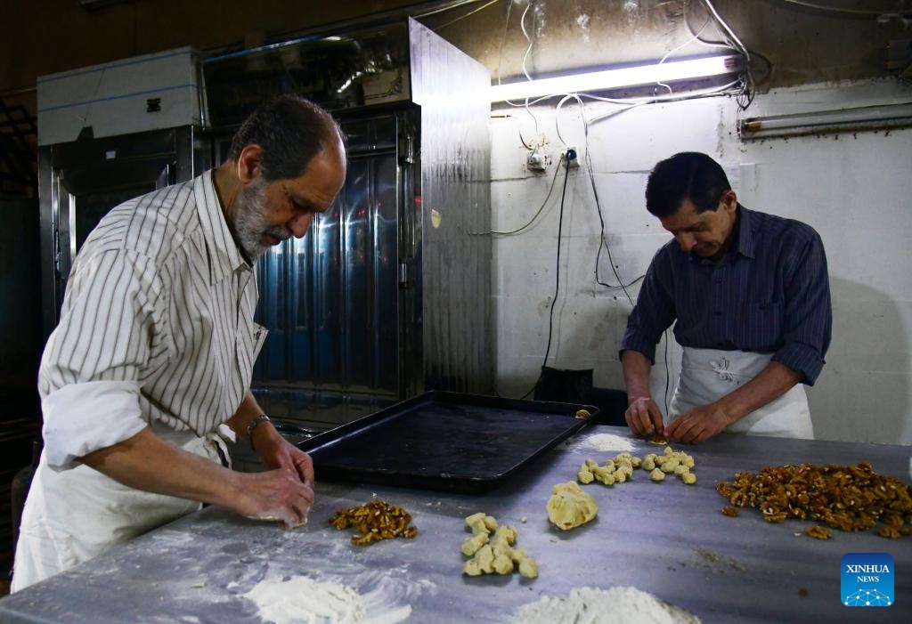 Two Syrian bakers prepare dough and fillings at a traditional sweets workshop in Damascus, Syria, on March 27, 2025. As Eid al-Fitr approaches, bakeries across Damascus are busy preparing maamoul and other confections made with wheat flour and stuffed with pistachios, walnuts or dates. (Photo: Xinhua)
