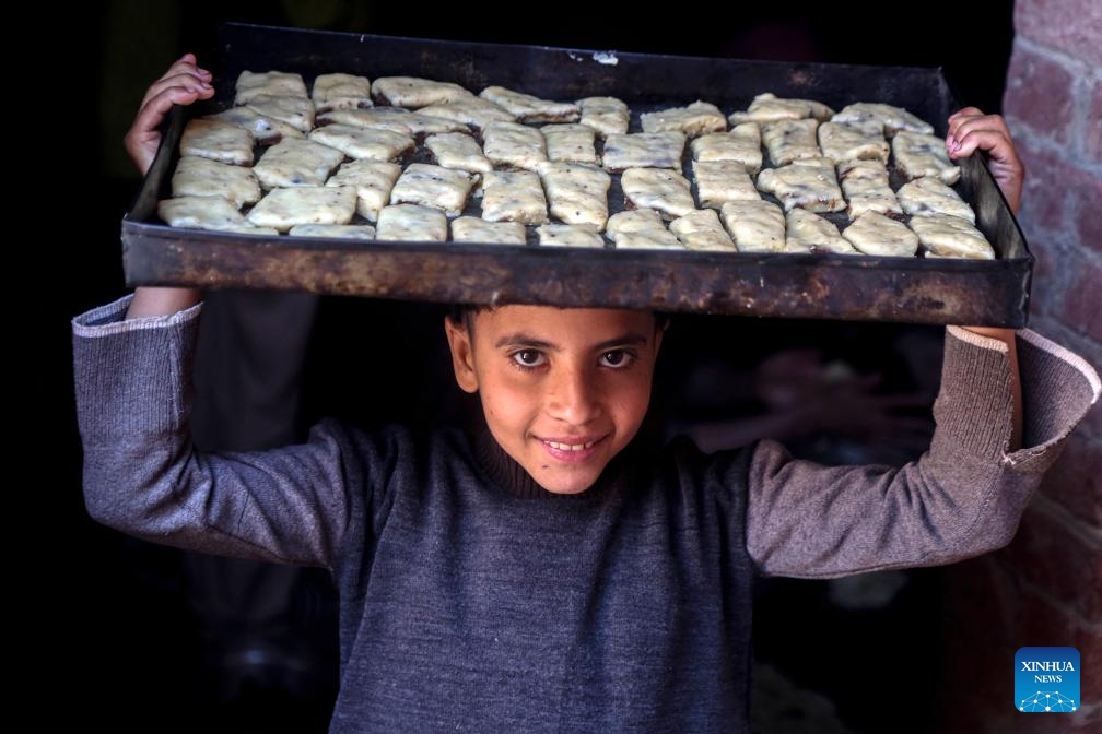 A child carries unfinished traditional cookies ahead of Eid al-Fitr in Cairo, Egypt, on March 27, 2025. (Photo: Xinhua)