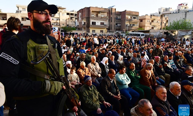 A security guard stands ready as people perform the special prayer of the Muslim Eid al-Fitr feast in Damascus, Syria, March 31, 2025. (Photo: Xinhua)