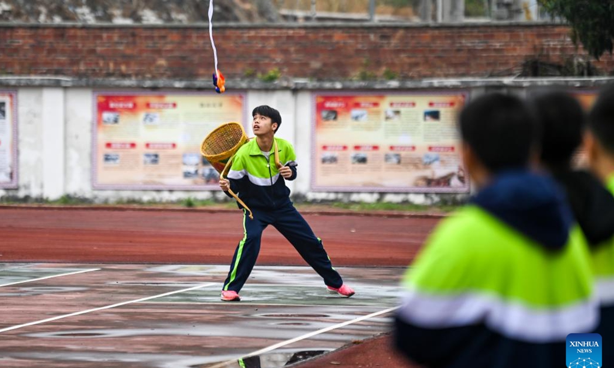 A student catches a embroidered ball with a basket in Yulin Ethnic Middle School in Yulin, south China's Guangxi Zhuang Autonomous Region, Feb. 19, 2025. Guangxi Zhuang Autonomous Region is the autonomous region with the largest population of ethnic minorities in China, with multiple ethnic groups such as Zhuang, Yao, Miao, and Dong who have lived there for generations. Throwing embroidered balls is a traditional sport that Guangxi people enjoy, carrying a profound folk heritage. In Zhuang culture, embroidered ball is a symbol of love. (Photo: Xinhua)

