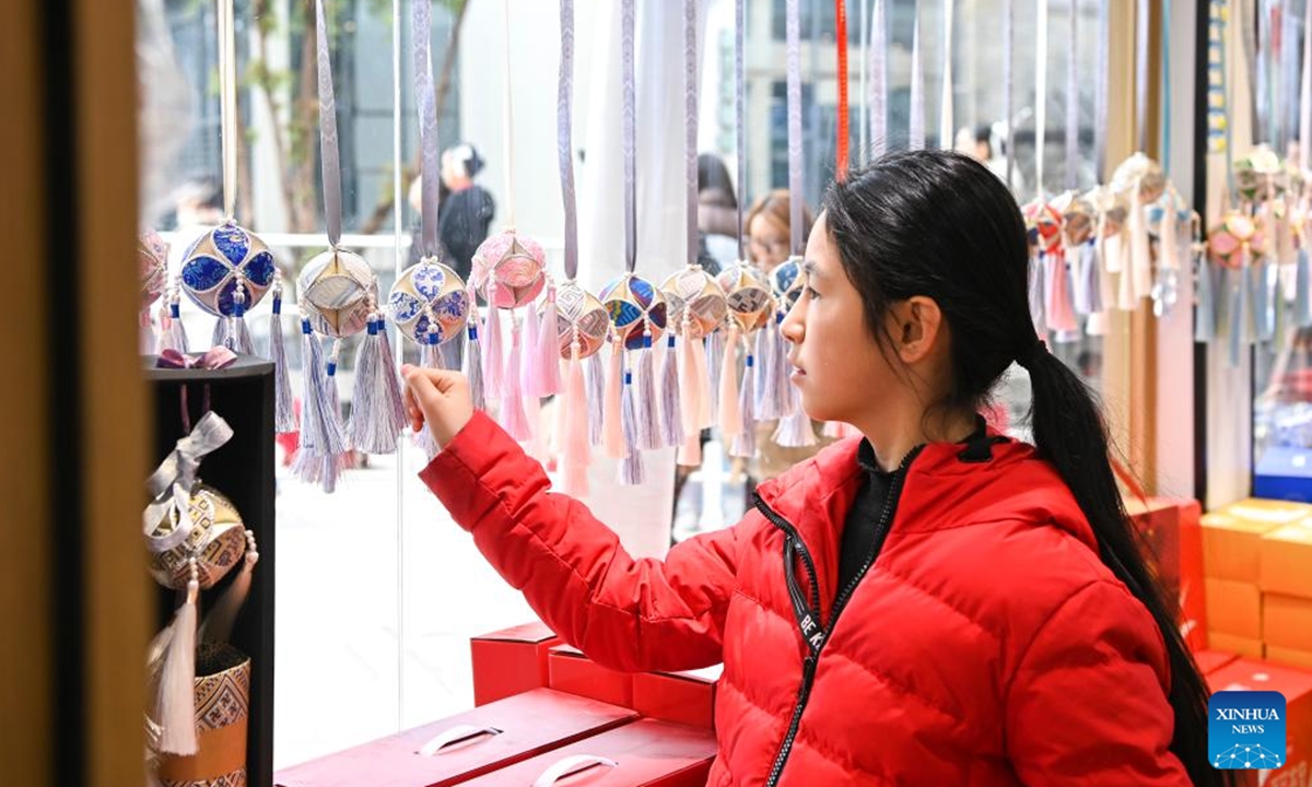 A customer chooses embroidered balls at a canival of the Sanyuesan Festival in Nanning, south China's Guangxi Zhuang Autonomous Region, March 31, 2025. Guangxi Zhuang Autonomous Region is the autonomous region with the largest population of ethnic minorities in China, with multiple ethnic groups such as Zhuang, Yao, Miao, and Dong who have lived there for generations. Throwing embroidered balls is a traditional sport that Guangxi people enjoy, carrying a profound folk heritage. In Zhuang culture, embroidered ball is a symbol of love. (Photo: Xinhua)

