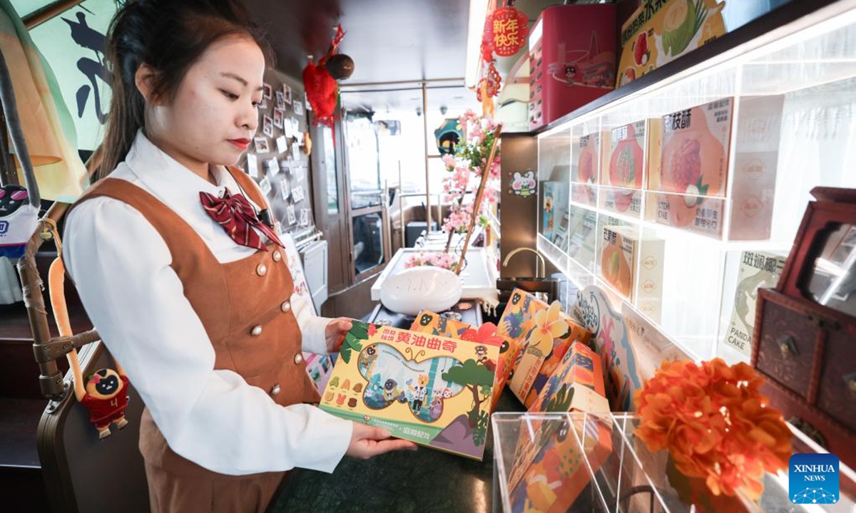 A crew member demonstrates a product, themed on the fifth China International Consumer Products Expo (CICPE), on the Laobacha Haikou Bus's CICPE special route in Haikou, south China's Hainan Province, April 6, 2025. Ahead of the upcoming fifth China International Consumer Products Expo (CICPE), the Laobacha Haikou Bus has inaugurated its CICPE special route. Laobacha is a beloved Hainan tradition where locals gather over fragrant tea, savory snacks, and leisurely chat..  (Photo: Xinhua)