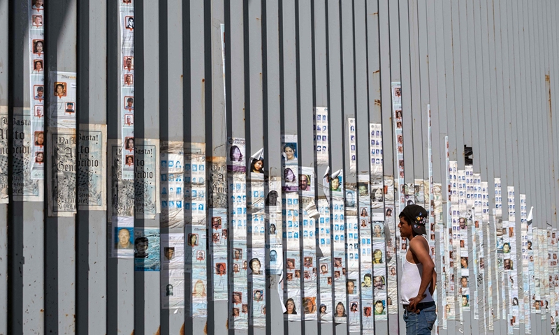 A man looks at photographs of missing persons attached to the Mexico-US border fence in Playas de Tijuana, Baja California State, Mexico, on April 17, 2025. Photo: VCG
