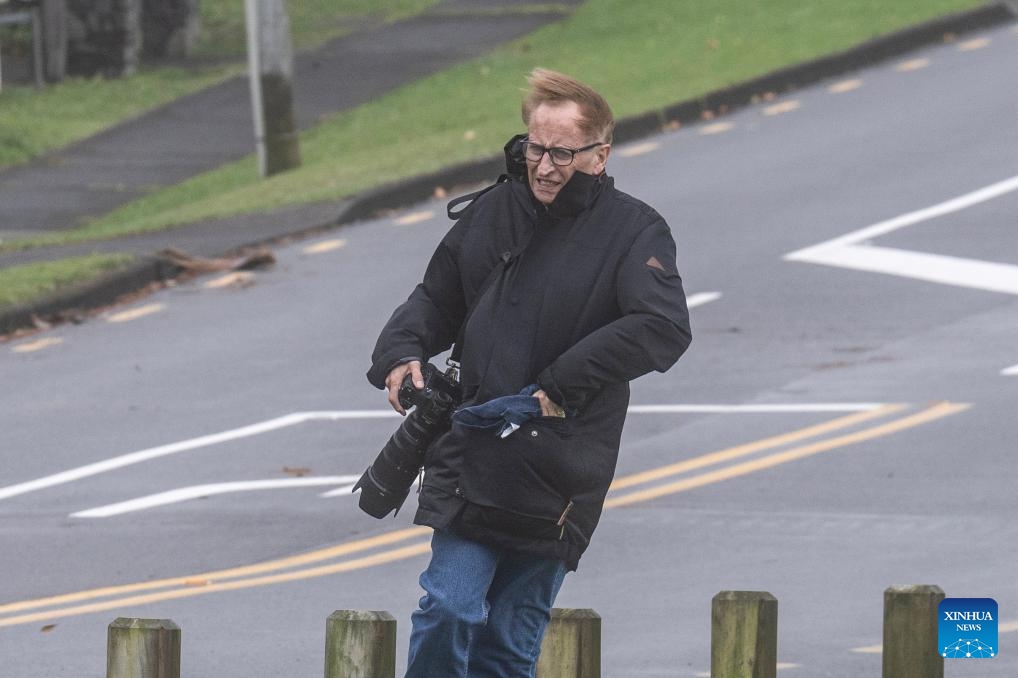 A photographer is seen on a street in Auckland, New Zealand, April 17, 2025. Ex-Tropical Cyclone Tam has unleashed severe weather across New Zealand's Northland and Auckland, leaving thousands without power and causing widespread damage as it tracks southward. (Photo: Xinhua)