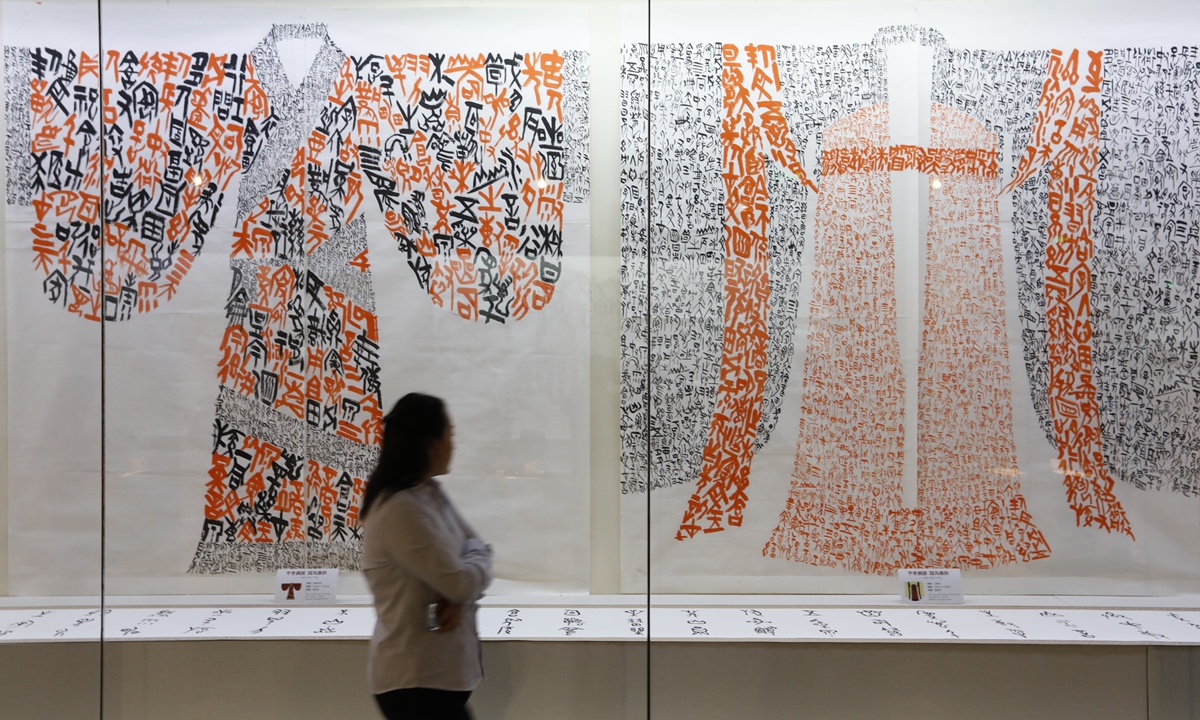 A visitor walks past two paintings of Hanfu made using oracle bone characters at the National Museum of Chinese Writing in Anyang, Central China's Henan Province, on Monday. The exhibition features five series of oracle bone art, including on bronzes, qipao and other artifacts. Photo: VCG