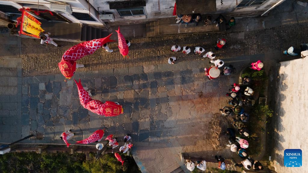 An aerial drone photo shows visitors enjoying performance of fish-shaped lanterns at Yuliang ancient town in Shexian County of Huangshan City, east China's Anhui Province, March 24, 2025. Located at the junction of Huangshan Mountains and Xin'an River, Shexian County of east China's Anhui Province has carried the essence of Hui-style culture and architecture. Huizhou Ancient City, lying at the heart of Shexian, is one of the best-preserved ancient towns in China. Its network of ancient streets, alleys, and bridges is complemented by traditional residences, ancestral halls, and memorial archways. (Photo: Xinhua)