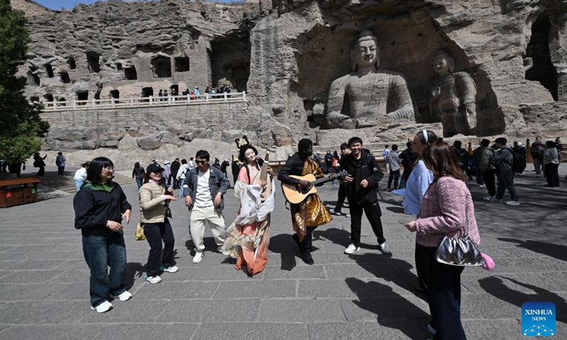 Actors dressed in costume interact with tourists at Yungang Grottoes in Datong, north China's Shanxi Province, April 15, 2025. Yungang Grottoes was built during the Northern Wei Dynasty (386-534). It is considered a pinnacle of Chinese Buddhist art and represents the highest level of sculptural artistry in the world during the 5th century. In recent years, Shanxi has made great efforts to protect and study the grottoes. In 2021, the research institute of the Yungang Grottoes was established for the protection, research and management of the Yungang Grottoes. (Photo: Xinhua)