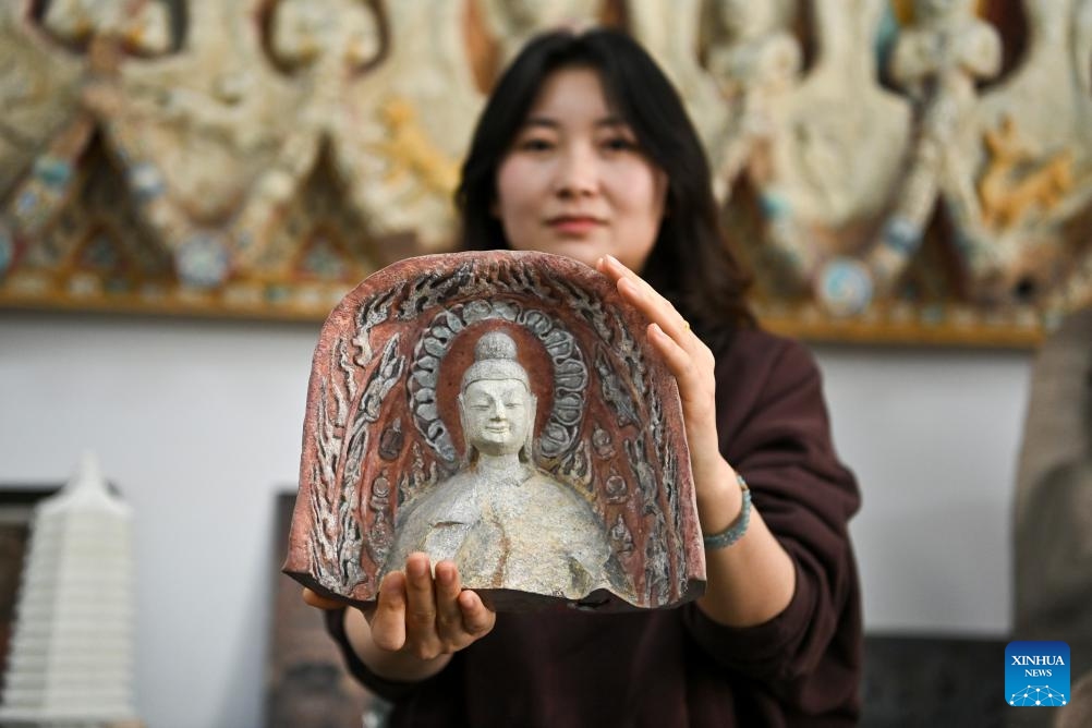 Wang Na, a staff member of the research institute of the Yungang Grottoes, displays a 3D-printed Buddha statue at an exhibition hall of the institute in Datong, north China's Shanxi Province, April 16, 2025. Yungang Grottoes was built during the Northern Wei Dynasty (386-534). It is considered a pinnacle of Chinese Buddhist art and represents the highest level of sculptural artistry in the world during the 5th century. (Photo: Xinhua)