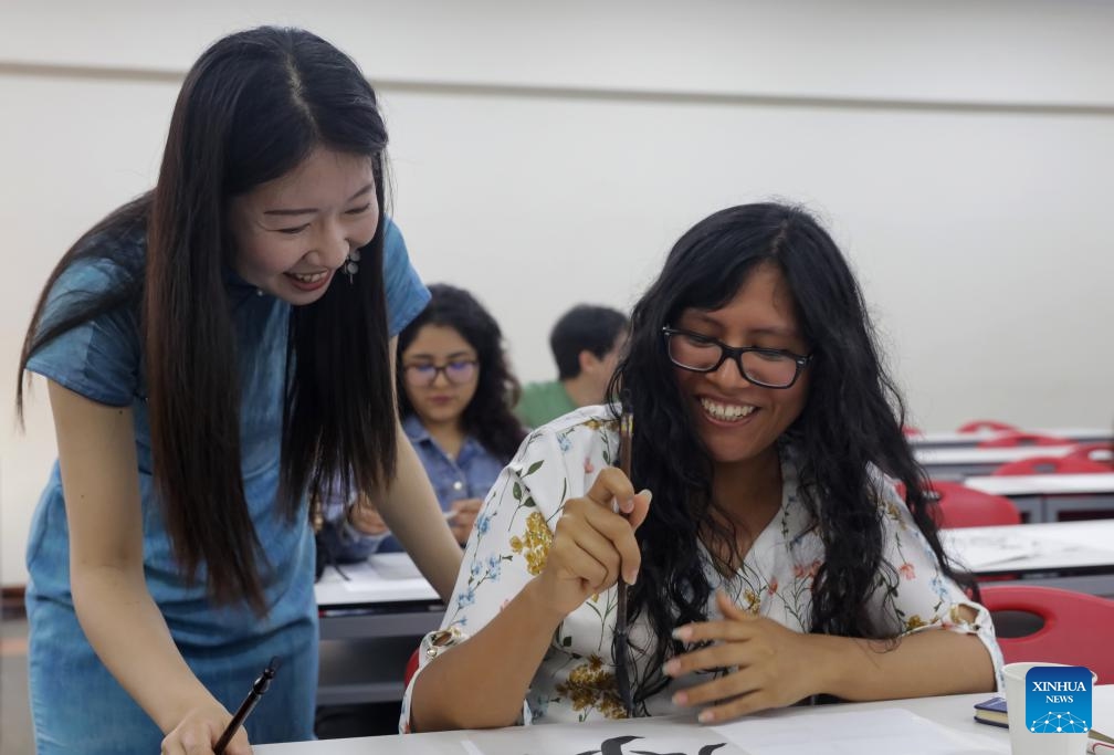 Liang Qing (L), a Chinese language teacher at the Confucius Institute of the Pontifical Catholic University of Peru, instructs a Peruvian student in writing Chinese calligraphy in Lima, capital of Peru, April 22, 2025. A series of activities to celebrate the International Chinese Language Day was held here on Tuesday by the Pontifical Catholic University of Peru. (Photo: Xinhua)