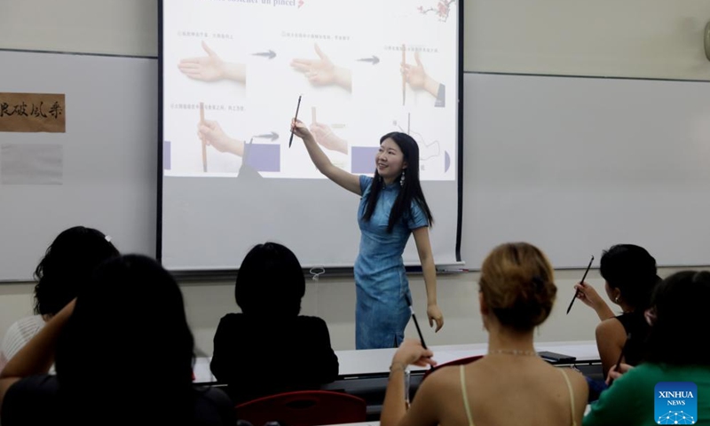 Liang Qing, a Chinese language teacher at the Confucius Institute of the Pontifical Catholic University of Peru, explains Chinese calligraphy to Peruvian students in Lima, capital of Peru, April 22, 2025. A series of activities to celebrate the International Chinese Language Day was held here on Tuesday by the Pontifical Catholic University of Peru. (Photo: Xinhua)