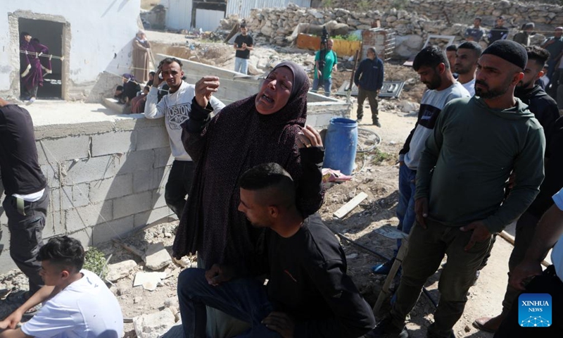 Palestinians are seen as Israeli excavators demolish a house in the village of Idna, west of the West Bank city of Hebron, on April 28, 2025. The houses here were demolished due to a lack of Israeli-issue building permits, which Palestinians say are nearly impossible to obtain. (Photo: Xinhua)