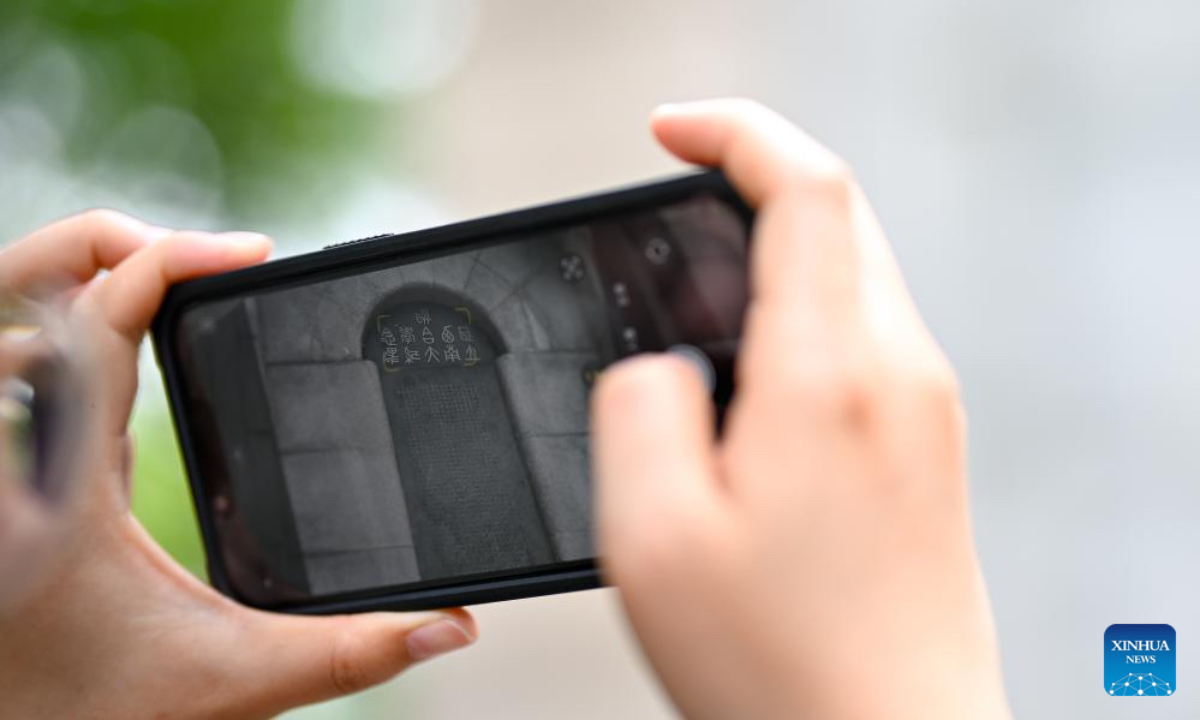 Yang Yali takes a photo of a monument of the National Southwest Associated University at the Balitai Campus of Nankai University in north China's Tianjin, May 8, 2025. (Xinhua/Zhang Cheng)