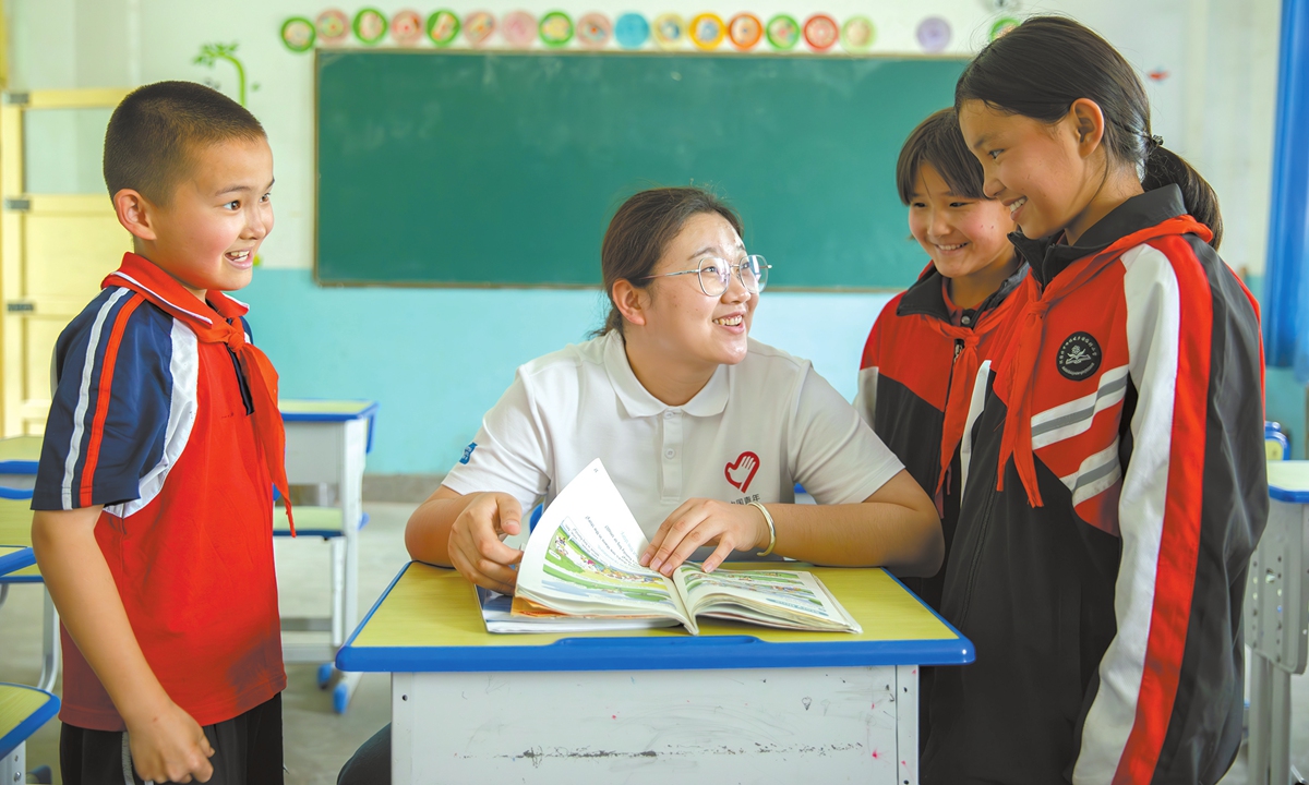 A volunteer teacher at the Xieyite Primary School in Northwest China's Xinjiang Uygur Autonomous Region, talks with students. Photo: Courtesy of Yang Jie