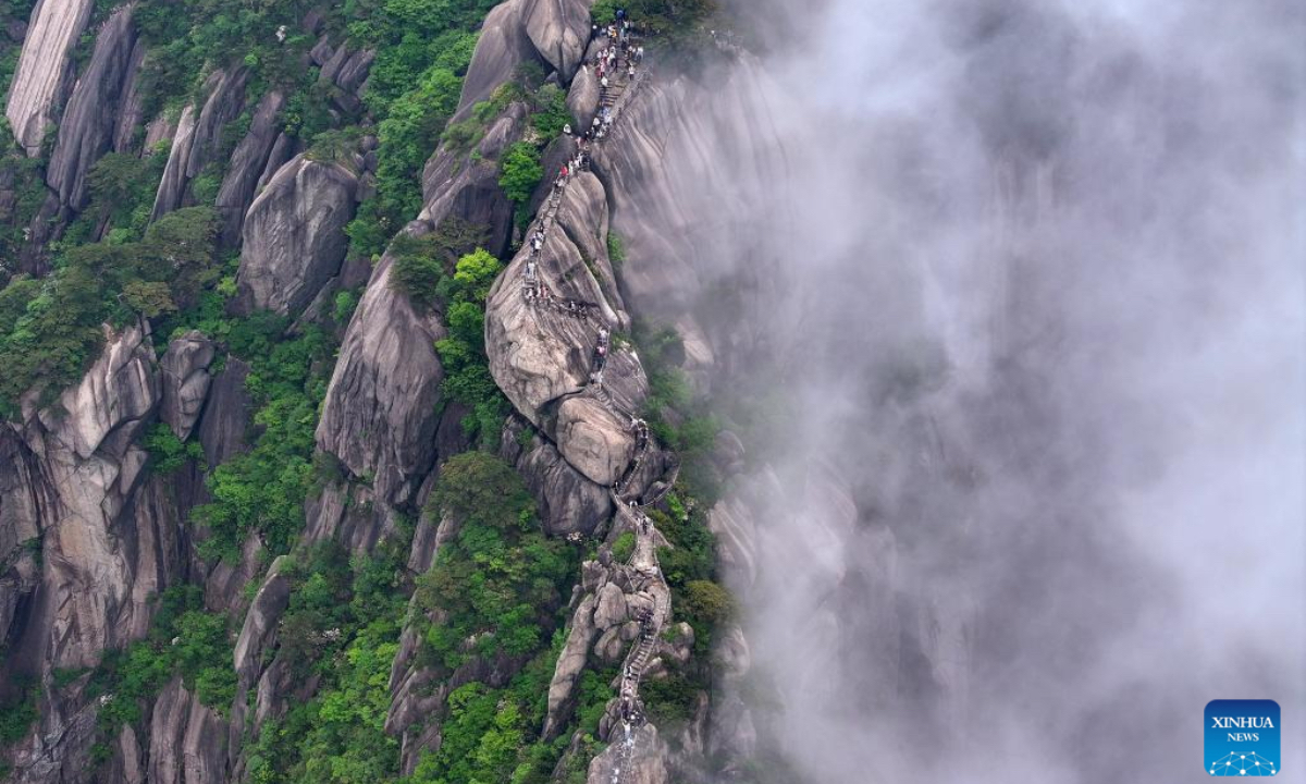 An aerial drone photo taken on May 20, 2024 shows tourists visiting the Tiandu Peak as it resumed opening in Huangshan Scenic Area in east China's Anhui Province. Huangshan Mountain is a listed UNESCO World Cultural and Natural Heritage Site, which has attracted a large number of tourists. To minimize the impact of visitors on its vegetation growth, the Huangshan Scenic Area rotates days off for its major scenic spots, as a special arrangement for ecological protection. The Tiandu Peak, one of the most popular sites in the Huangshan scenic area, ended its more than five-year 
