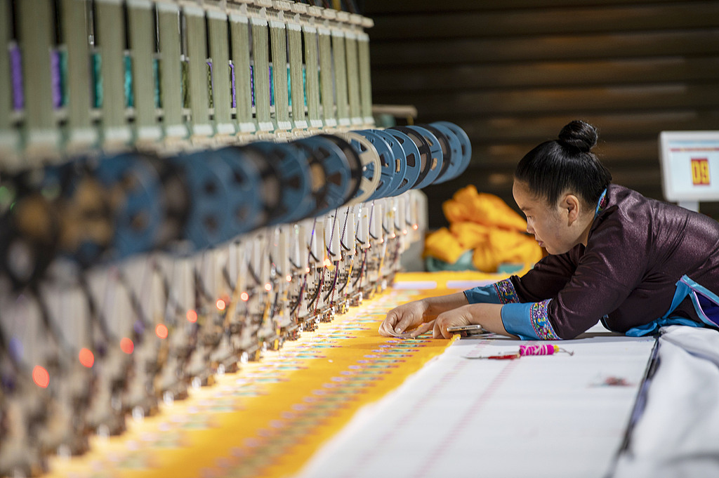 A woman does Miao embroidery using a Computer Numerical Control machine tool in a workshop in Qiandongnan Miao and Dong Autonomous Prefecture, Southwest China's Guizhou Province, on May 9, 2025. In 2024, the total output value of 139 intangible cultural heritage workshops in the prefecture exceeded 450 million yuan ($62 million), helping to increase the incomes of many rural women in the region. Photo: VCG