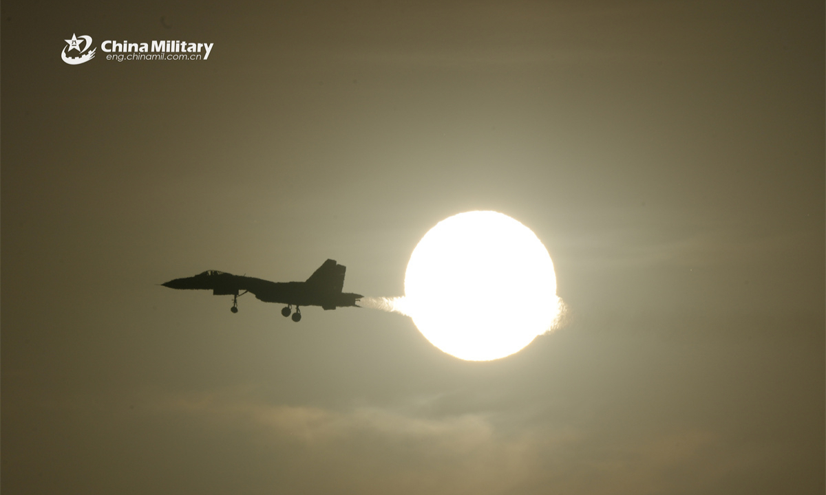 A fighter jet attached to a base under the Chinese PLA Naval Aviation University cuts a sharp shadow across the sun's molten glow during a recent flight training exercise. (eng.chinamil.com.cn/Photo by Wan Quan)