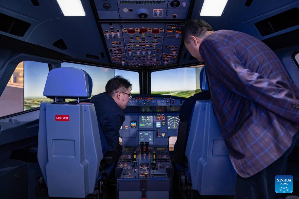 People try a simulated cockpit of a passenger aircraft at the 34th Harbin International Economic and Trade Fair in Harbin, capital of northeast China's Heilongjiang Province, May 19, 2025. The fair showcased cutting-edge technologies such as autonomous driving, commercial satellites and humanoid robots from over 100 tech firms. (Xinhua/Xie Jianfei)