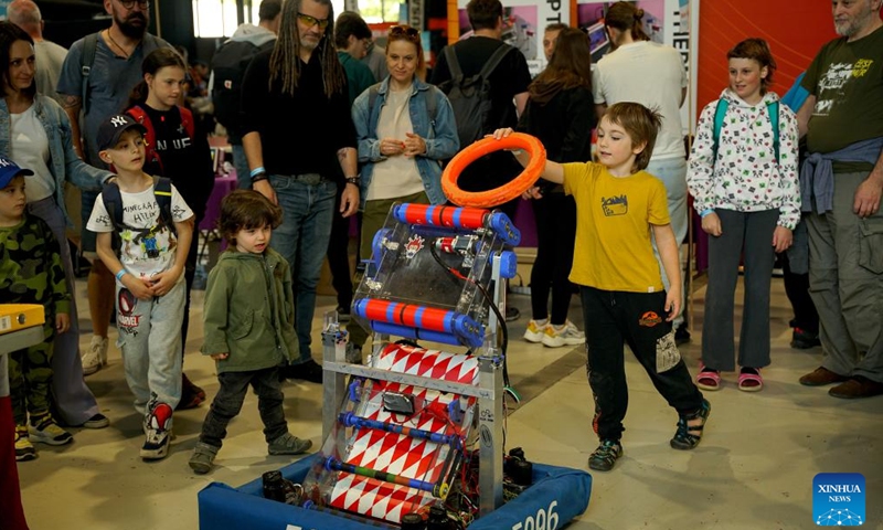 A boy inserts a rubber ring into a robot during the Maker Faire Prague 2025 in Prague, the Czech Republic, May 11, 2025.
