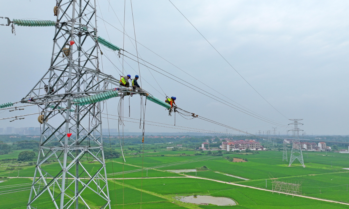 Workers inspect high-voltage transmission lines erected at a height that will ensure electricity safety in Liyuan village, Ji'an city, East China's Jiangxi Province, on May 25, 2025. Photo: VCG 