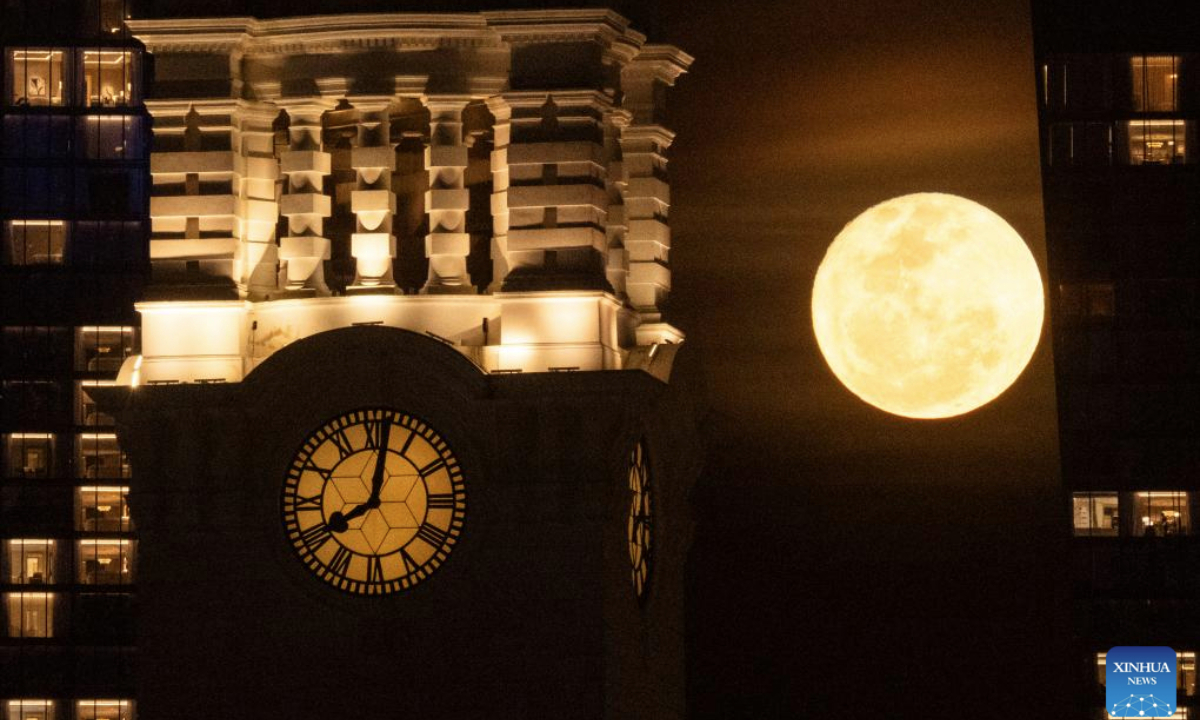 A full moon rises behind the clock tower of the Victoria Theatre and Victoria Concert Hall in Singapore on May 13, 2025. (Xinhua/Then Chih Wey)