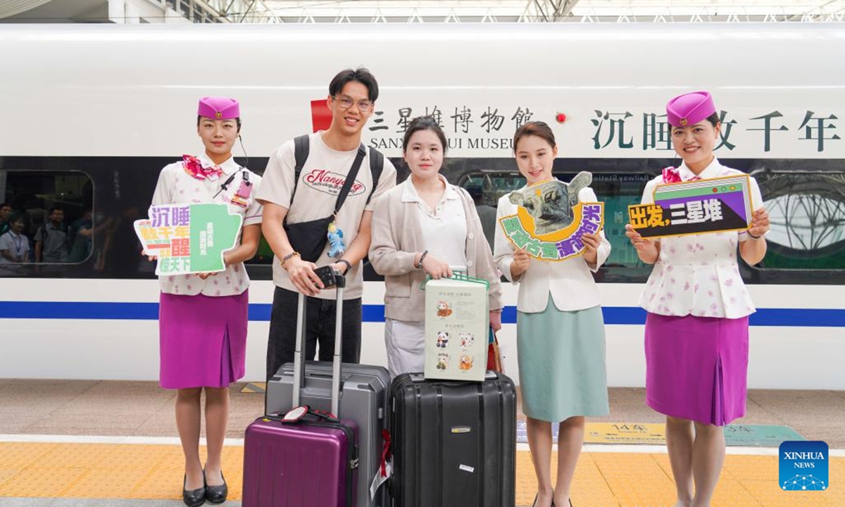 Passengers and train crew members pose for a group photo in front of a Sanxingdui-themed train at Chengdu East Railway Station in Chengdu, southwest China's Sichuan Province, May 18, 2025. The tourist train left Chengdu on Sunday, marking the launch of the first train themed around the legendary Sanxingdui Ruins site. (Photo: Xinhua)