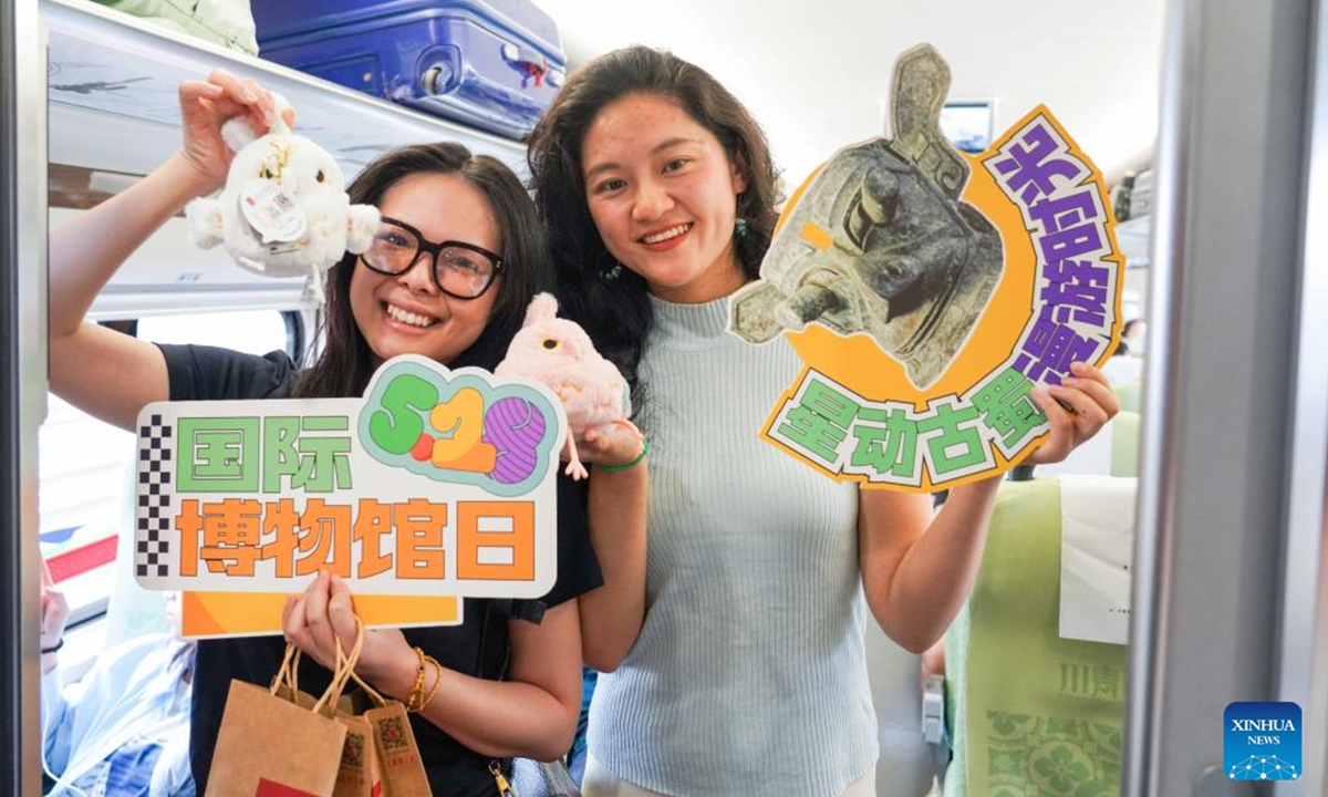 Passengers pose for a photo on a Sanxingdui-themed train linking Chengdu, Sanxingdui Ruins and Jiuzhai Valley in southwest China's Sichuan Province, May 18, 2025. The tourist train left Chengdu on Sunday, marking the launch of the first train themed around the legendary Sanxingdui Ruins site.(Photo: Xinhua)