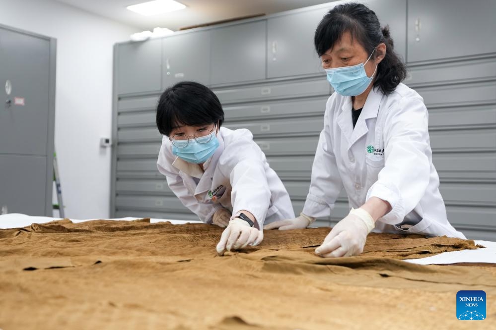 Suzhou Silk Museum staff members Chen Yanlu (L) and Meng Xiaochou arrange a silk garment dating back to the Ming Dynasty (1368-1644) in Suzhou, east China's Jiangsu Province, May 18, 2025.