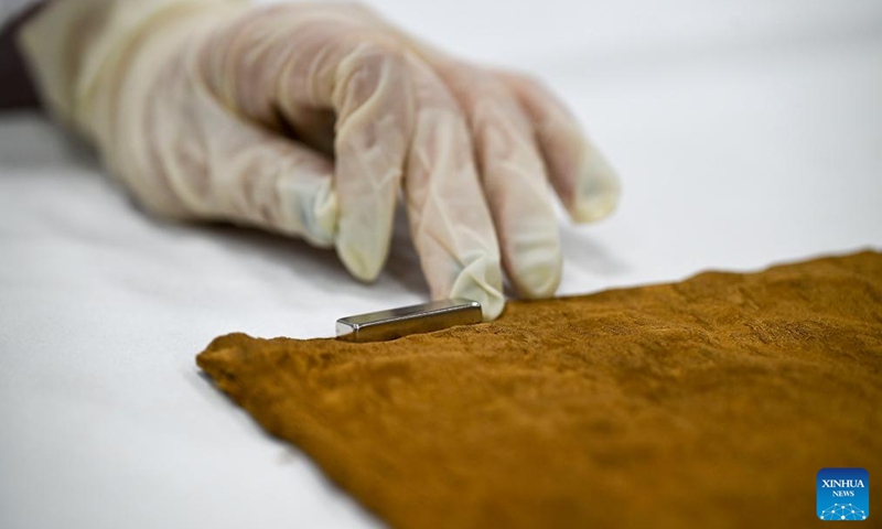 Suzhou Silk Museum staff member Chen Yanlu uses a magnet to flatten a silk cultural clothing against an iron workbench in Suzhou, east China's Jiangsu Province, May 18, 2025. (Xinhua/Li Bo)