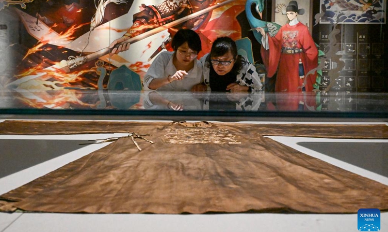 Suzhou Silk Museum staff member Meng Xiaochou (R) introduces a cultural relic she restored years ago for her colleague Chen Yanlu in Suzhou, east China's Jiangsu Province, May 18, 2025. (Xinhua/Chen Shuo)