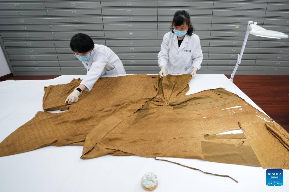 Suzhou Silk Museum staff members Chen Yanlu (L) and Meng Xiaochou arrange a silk garment dating back to the Ming Dynasty (1368-1644) in Suzhou, east China's Jiangsu Province, May 18, 2025. Restoration of this cultural relic has been ongoing for more than three months. (Xinhua/Li Bo)