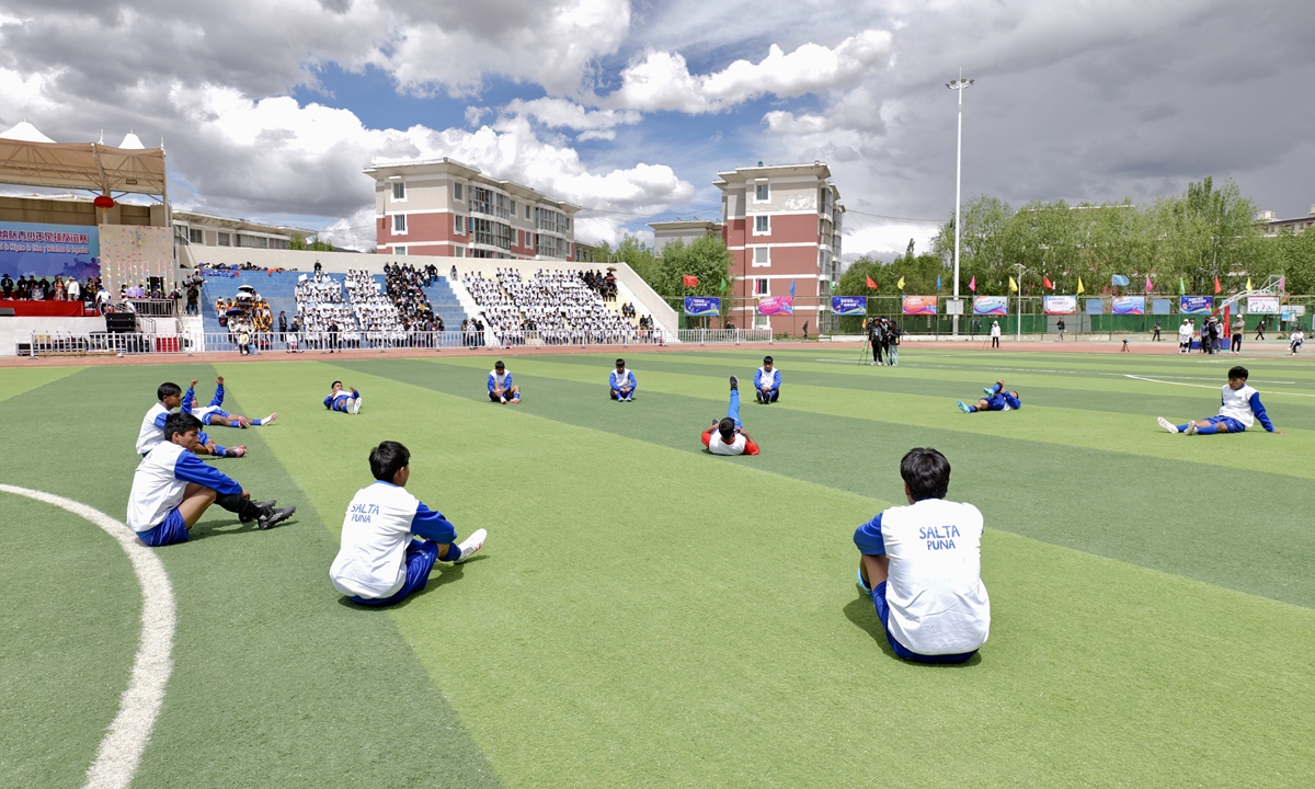 Players of the Argentine Salta delegation team warm up on the field before the football match in Xigaze on May 20, 2025. 