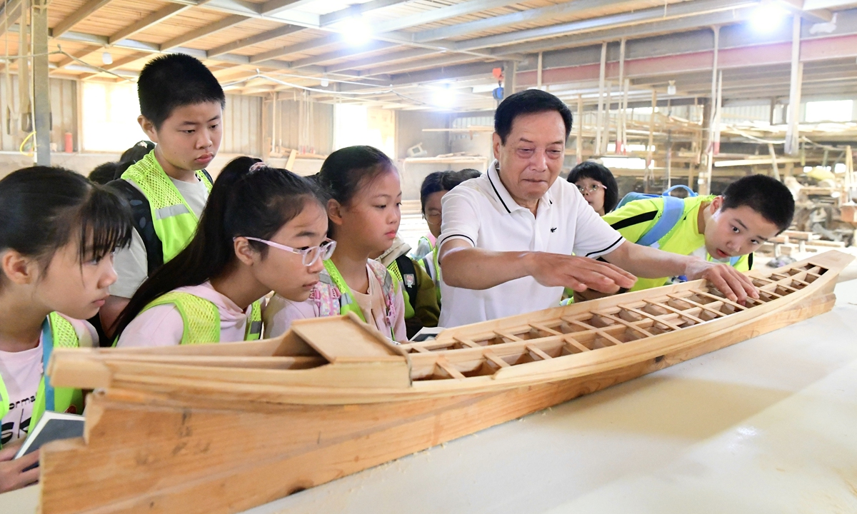 Fang Shaohuang, a third-generation inheritor of Fangzhuang dragon boat making skills, a Fuzhou city-level intangible cultural heritage, explains the traditional techniques and production of making dragon boats  to visiting primary school students on May 25, 2025 at the Fang Zhongxiong dragon boat workshop in Fuzhou, East China's Fujian Province. Photo: VCG