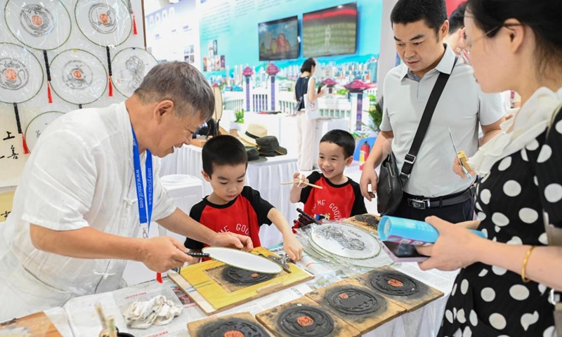 Children experience a traditional Chinese printing skill at the exhibition area of Jiangxi Province during the 21st China (Shenzhen) International Cultural Industries Fair in Shenzhen, south China's Guangdong Province, May 24, 2025. Opened here on Thursday, the five-day event is being held across eight exhibition halls -- three comprehensive spaces and five specialized areas. Activities related to traditional culture and cultural heritages attracted many young visitors. Photo: Xinhua