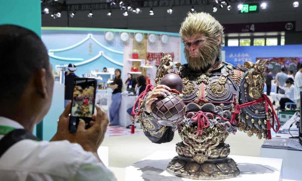 A visitor takes photos of a Black Myth: Wukong bust at the 21st China (Shenzhen) International Cultural Industries Fair in Shenzhen, south China's Guangdong Province, May 23, 2025. (Xinhua/Liang Xu)
