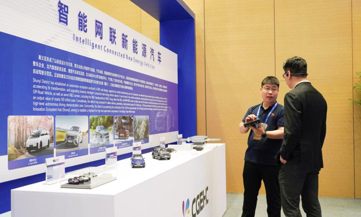 A staff member introduces intelligent connected new energy vehicles to a participant during an event of the China-Germany (China-Europe) Hidden Champions Forum 2025 in Beijing, capital of China, May 26, 2025. The China-Germany (China-Europe) Hidden Champions Forum 2025 kicked off here on Monday. (Xinhua/Zhang Chenlin)