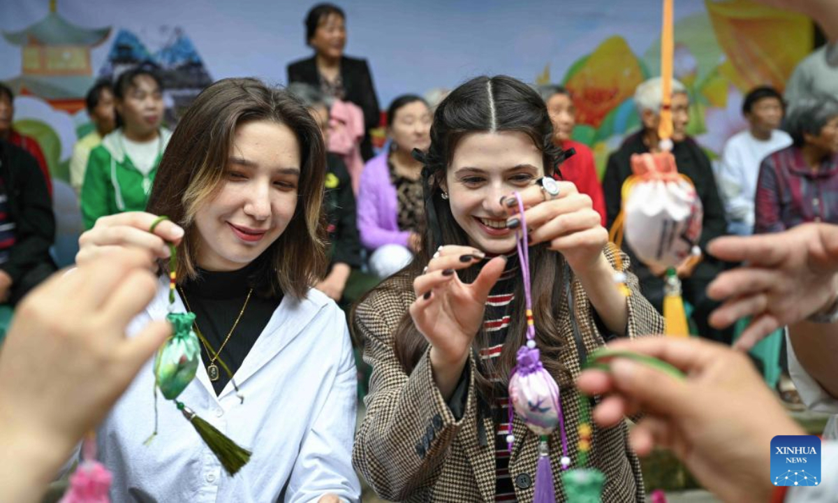 Local residents and international students try to make sachets at Fengsheng ancient town of Banan District in southwest China's Chongqing Municipality, May 28, 2025. Over 200 local residents and international students from Chongqing University participated in a cultural experience activity ahead of the Dragon Boat Festival, which falls on the fifth day of the fifth month in the Chinese lunar calendar. (Xinhua/Chen Cheng)