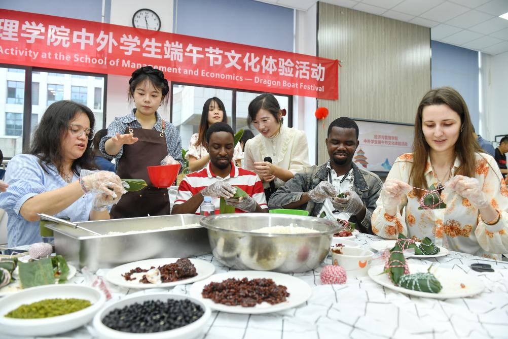 International students learn to make zongzi, a traditional Chinese food to mark the Dragon Boat Festival, at University of Electronic Science and Technology of China in Chengdu, southwest China's Sichuan Province, on May 30, 2025. The Dragon Boat Festival, also known as Duanwu Festival, is a traditional Chinese holiday to commemorate ancient Chinese poet Qu Yuan from the Warring States Period (475-221 B.C.). Celebrated on the fifth day of the fifth month of the Chinese lunar calendar, the festival falls on May 31 this year. (Photo by Li Xiangyu/Xinhua)