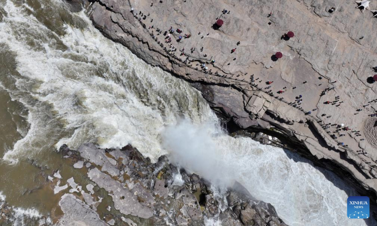 An aerial drone photo taken on June 4, 2025 shows tourists visiting the Hukou Waterfall on the Yellow River on the border between north China's Shanxi Province and northwest China's Shaanxi Province. (Xinhua/Zhang Bowen)