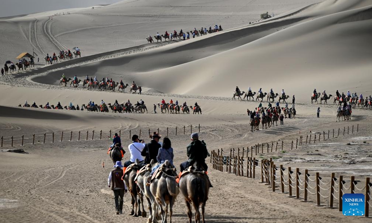 People ride camels at the Mingsha Mountain and Crescent Spring scenic spot in Dunhuang, northwest China's Gansu Province, June 2, 2025. People enjoy the 3-day holiday of the Dragon Boat Festival, also called Duanwu Festival which falls on May 31 this year, via various activities across the country. (Photo by Zhang Xiaoliang/Xinhua)