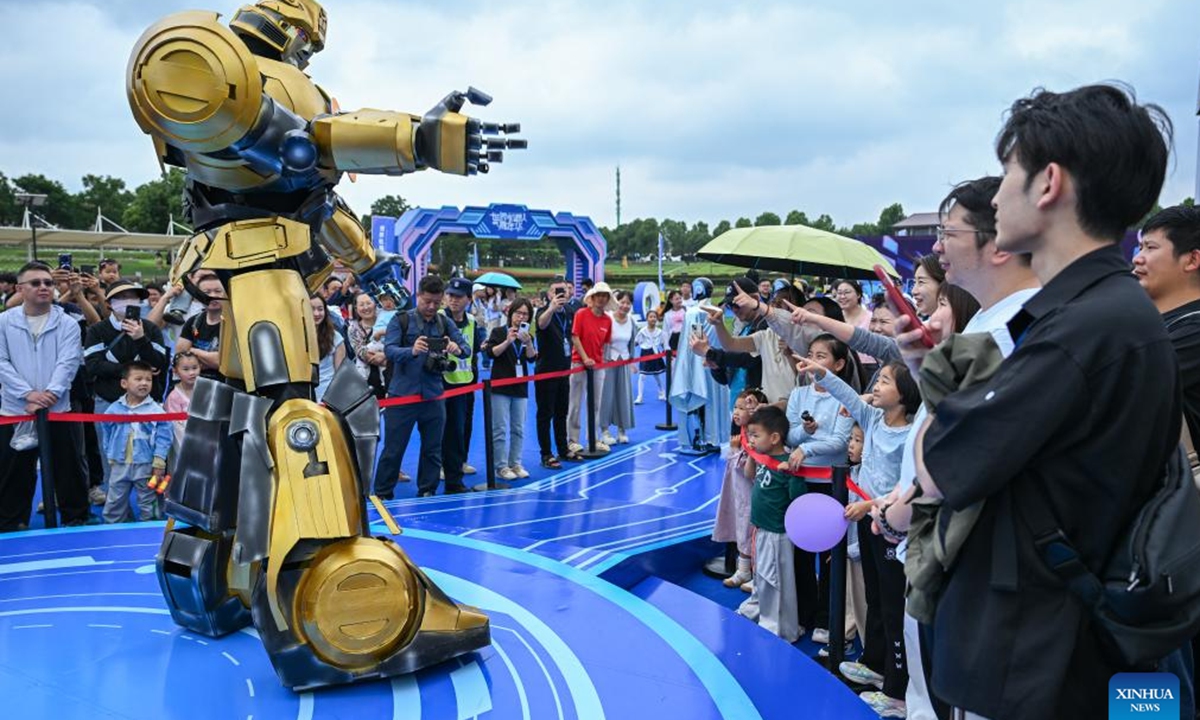Visitors interact with a robot during the world robot carnival in Wuhan, central China's Hubei Province, June 2, 2025. The event kicked off here on Monday, featuring nearly 100 robots including pet robots, make-up robots, robotics band, etc. People interacted with the robots to experience the charm of technology-empowered life. (Xinhua/Du Zixuan)