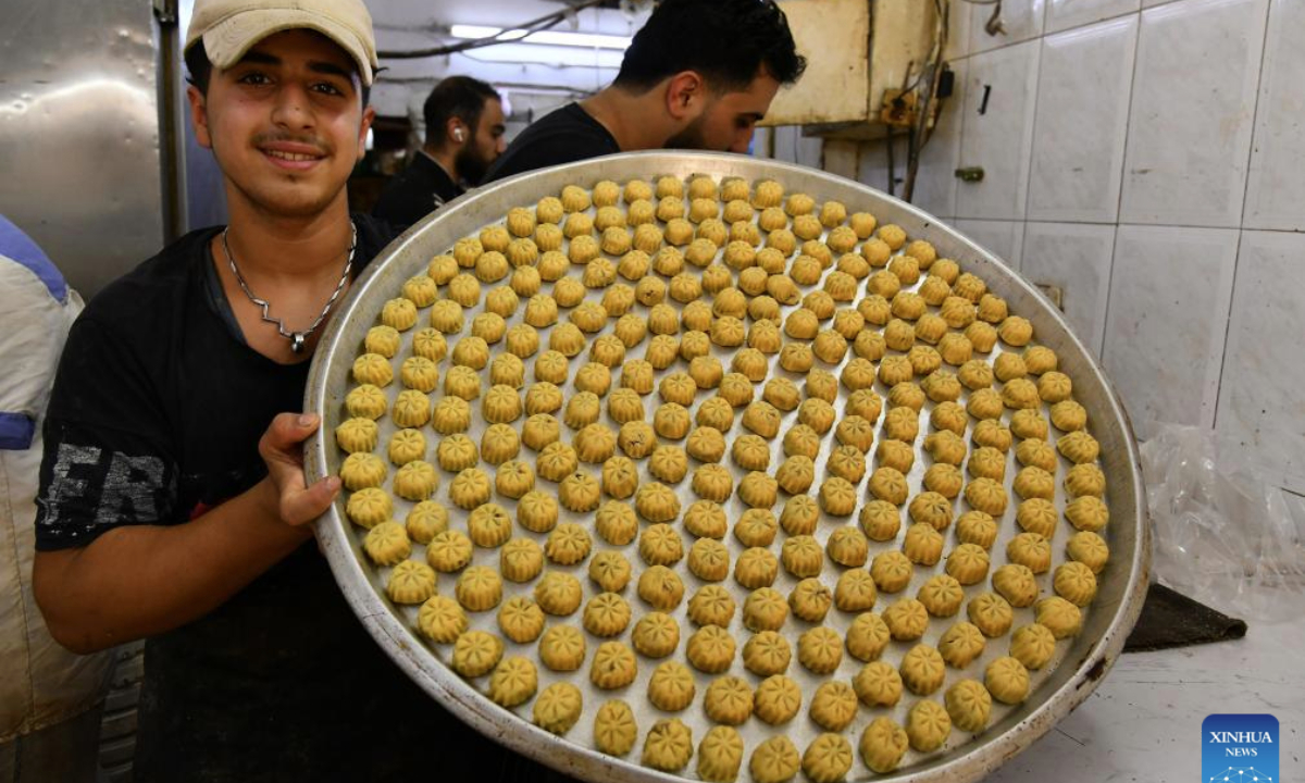 A man presents a tray of cookies at a sweets bakery ahead of Eid al-Adha in Damascus, Syria, on June 4, 2025. Traditional sweets are widely prepared and exchanged during Eid celebrations. (Photo by Ammar Safarjalani/Xinhua)