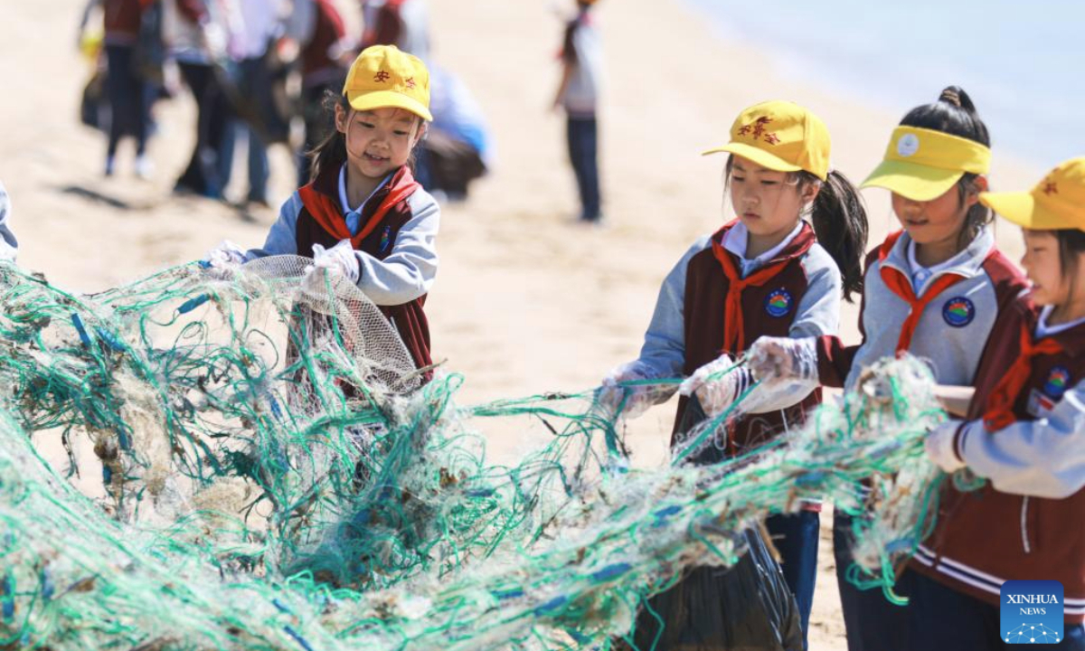 Primary school students clean up garbage at Binhai Park in Rongcheng City, east China's Shandong Province, on June 4, 2025. Various events are held to raise people's awareness of environmental protection in China ahead of World Environment Day, which falls on June 5. (Photo by Li Xinjun/Xinhua)