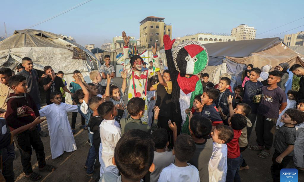 Palestinians dressed as clowns play with displaced children at a temporary shelter during Eid al-Adha in Gaza City, on June 6, 2025. (Photo by Rizek Abdeljawad/Xinhua)